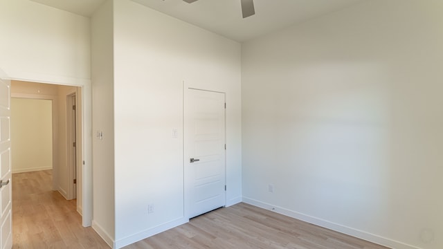 unfurnished bedroom with light wood-type flooring, ceiling fan, and a closet