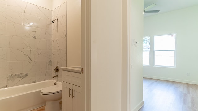 full bathroom with wood-type flooring, ceiling fan, tiled shower / bath, vanity, and toilet