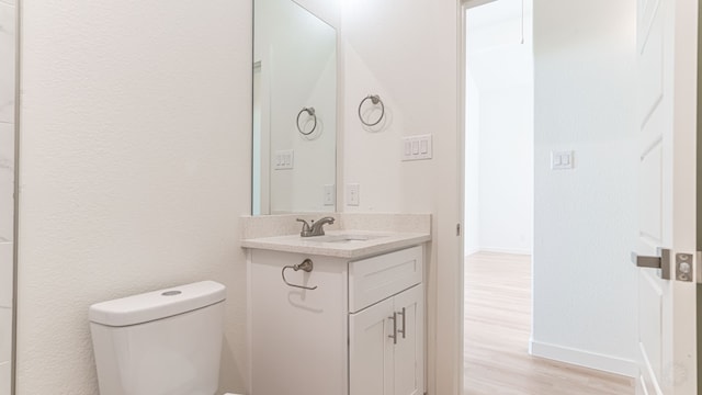 bathroom featuring wood-type flooring, vanity, and toilet