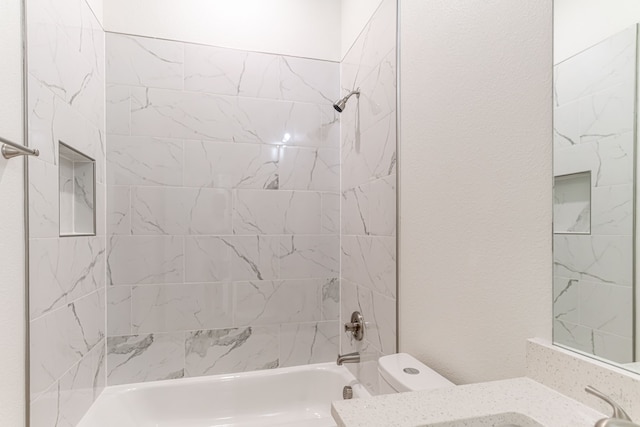 bathroom with toilet and tiled shower / bath