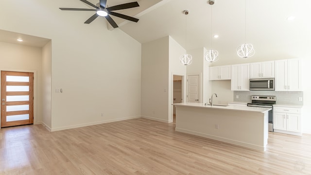 kitchen featuring appliances with stainless steel finishes, hanging light fixtures, a center island with sink, and white cabinets