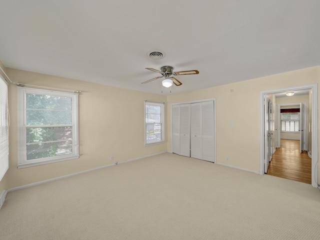 unfurnished bedroom with ceiling fan, light colored carpet, and a closet