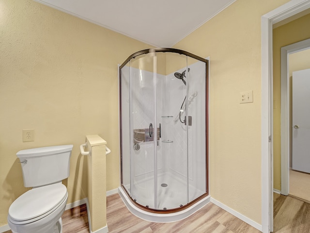 bathroom featuring a shower with door, toilet, and hardwood / wood-style flooring