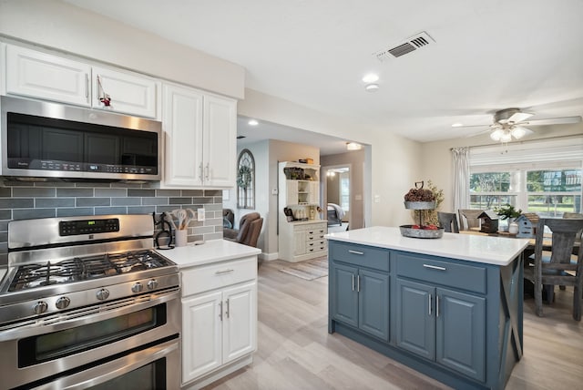 kitchen featuring light hardwood / wood-style floors, white cabinetry, stainless steel appliances, blue cabinets, and ceiling fan