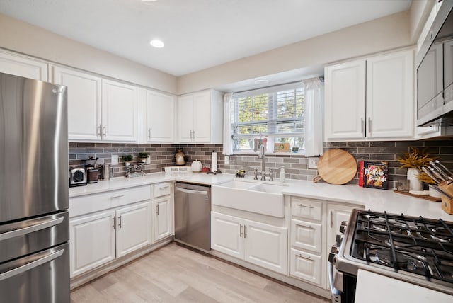 kitchen with light hardwood / wood-style flooring, appliances with stainless steel finishes, sink, and white cabinetry