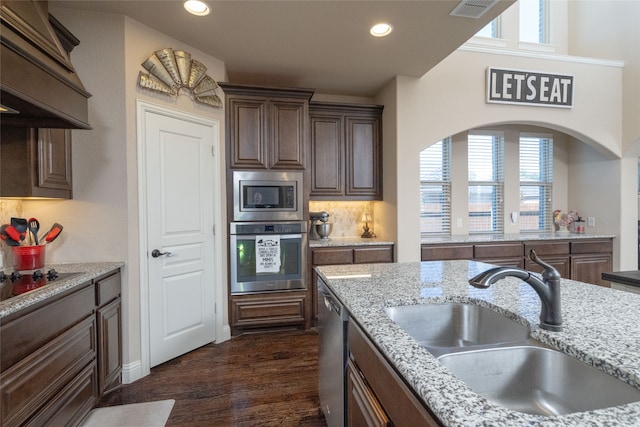 kitchen with stainless steel appliances, light stone countertops, sink, and a wealth of natural light