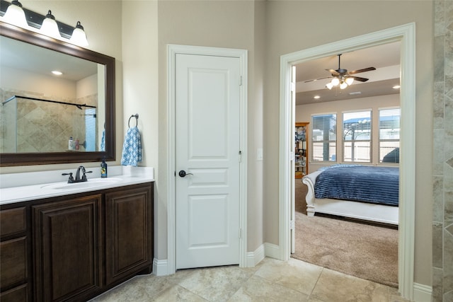 bathroom with ceiling fan, tiled shower, vanity, and tile patterned floors