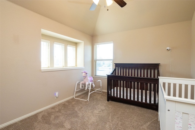 carpeted bedroom with a crib, ceiling fan, and vaulted ceiling