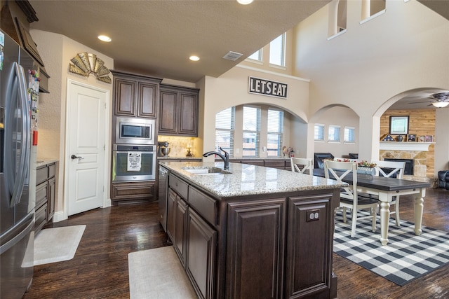 kitchen featuring sink, a kitchen island with sink, dark brown cabinets, stainless steel appliances, and plenty of natural light