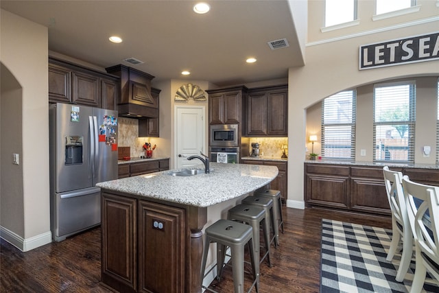 kitchen featuring dark brown cabinetry, sink, stainless steel appliances, and a center island with sink