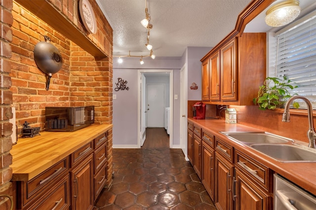 kitchen featuring butcher block countertops, dishwasher, sink, and a textured ceiling