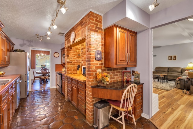 kitchen with a breakfast bar area, stainless steel appliances, a textured ceiling, dark hardwood / wood-style floors, and sink