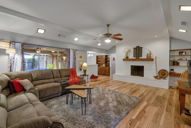 living room featuring ceiling fan, vaulted ceiling with beams, a brick fireplace, brick wall, and wood-type flooring