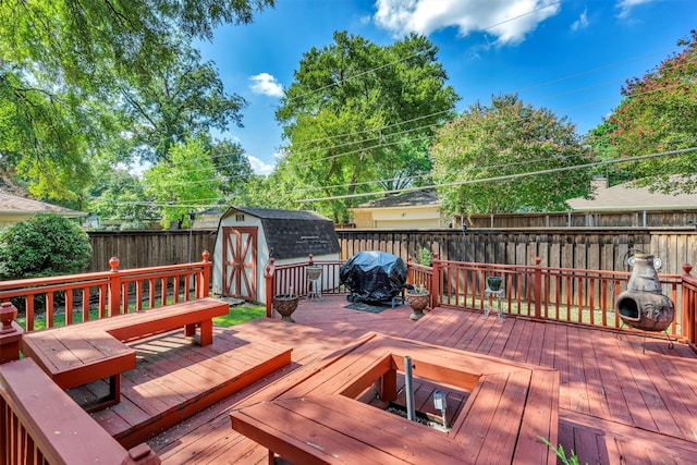 wooden terrace featuring area for grilling and a shed