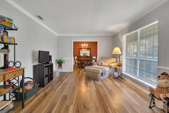 living room with light wood-type flooring, plenty of natural light, ornamental molding, and a notable chandelier