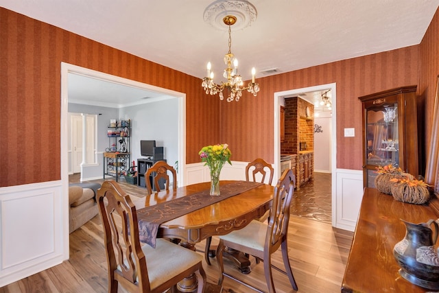 dining space with an inviting chandelier, light hardwood / wood-style flooring, and ornamental molding