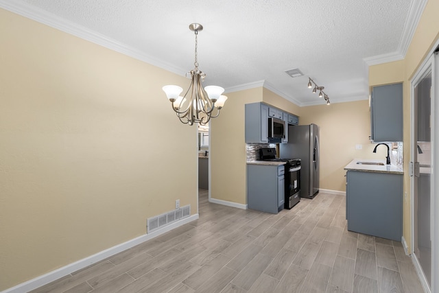 kitchen with light hardwood / wood-style floors, sink, rail lighting, an inviting chandelier, and appliances with stainless steel finishes