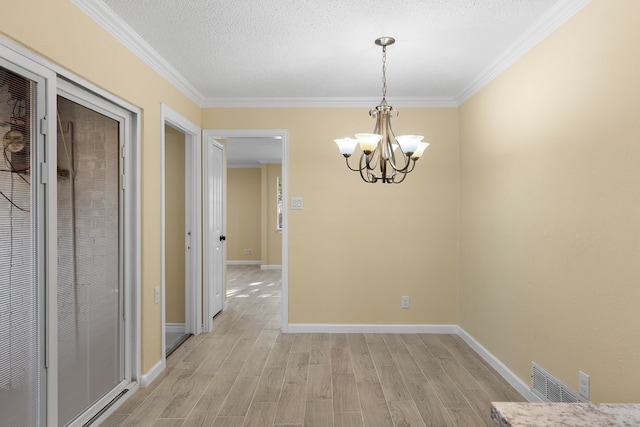 unfurnished dining area with a textured ceiling, light hardwood / wood-style floors, ornamental molding, and a chandelier