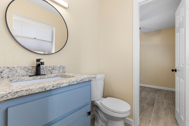 bathroom featuring wood-type flooring, vanity, and toilet