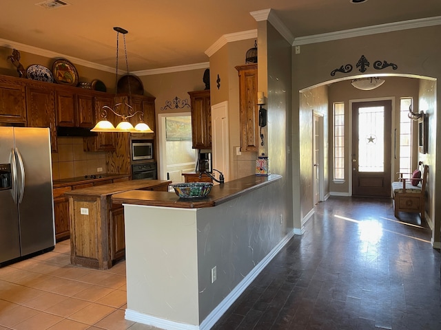 kitchen featuring pendant lighting, sink, ornamental molding, appliances with stainless steel finishes, and kitchen peninsula