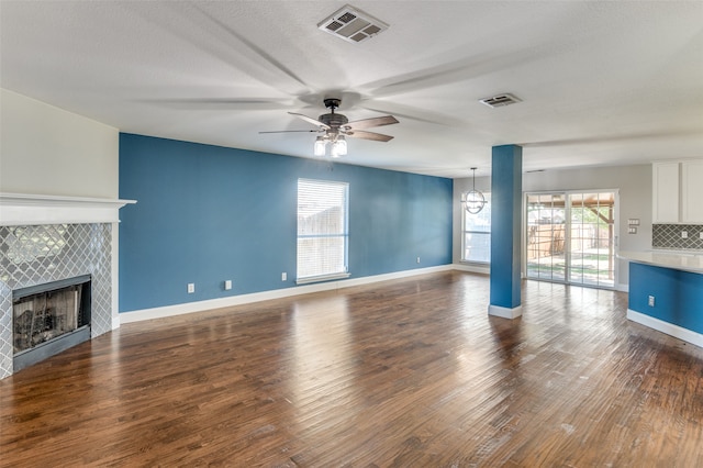 unfurnished living room with a fireplace, ceiling fan, dark hardwood / wood-style floors, and a textured ceiling