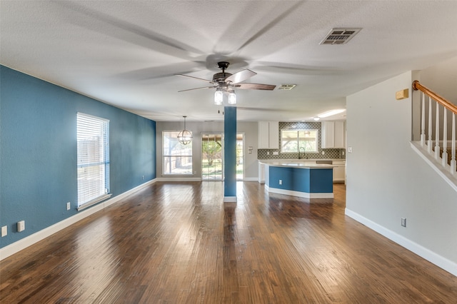 unfurnished living room with ceiling fan, dark wood-type flooring, and a textured ceiling