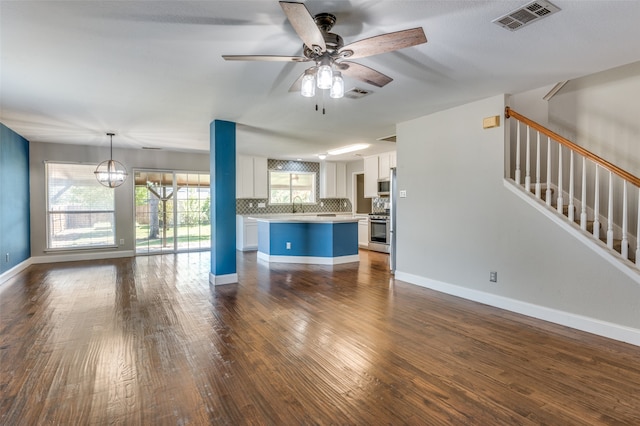 unfurnished living room featuring ceiling fan with notable chandelier, dark hardwood / wood-style flooring, and sink