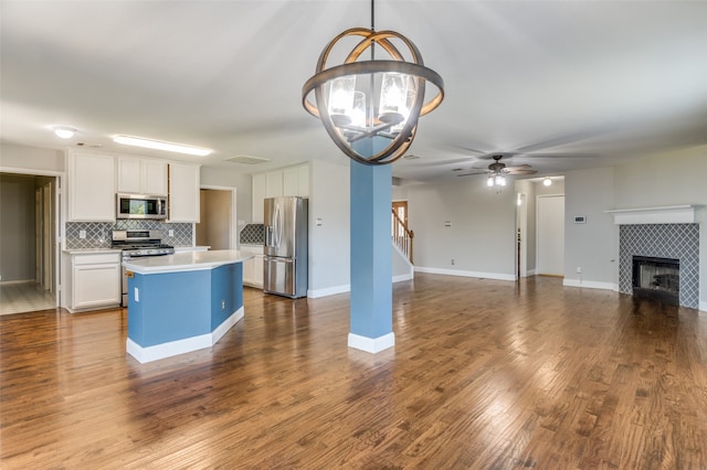 kitchen with a kitchen island, hardwood / wood-style floors, white cabinets, pendant lighting, and appliances with stainless steel finishes