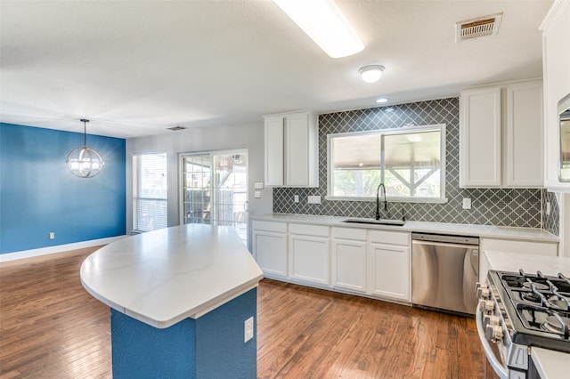 kitchen featuring dark hardwood / wood-style floors, stainless steel appliances, sink, pendant lighting, and white cabinetry