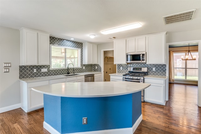 kitchen with stainless steel appliances, pendant lighting, dark wood-type flooring, and sink