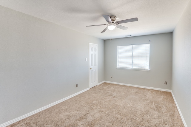 spare room featuring light carpet and ceiling fan