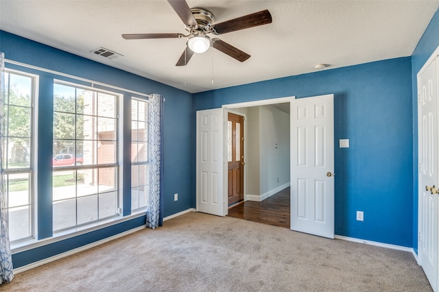 unfurnished bedroom with ceiling fan, carpet floors, and a textured ceiling