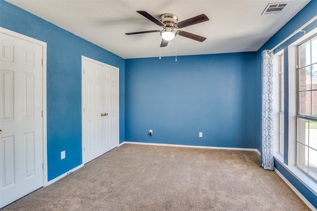 carpeted spare room with ceiling fan and a textured ceiling