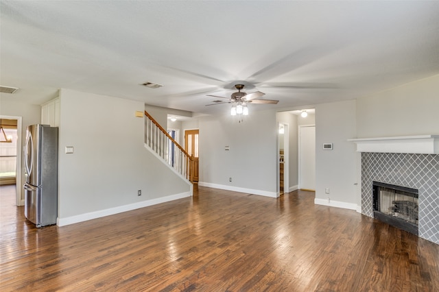 unfurnished living room with ceiling fan, a tile fireplace, and dark hardwood / wood-style floors