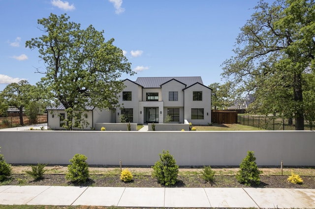 view of front of home with stucco siding, a fenced front yard, a standing seam roof, and metal roof