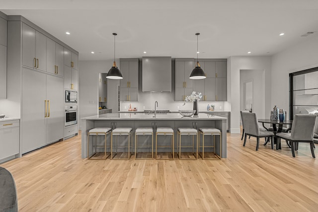 kitchen with gray cabinets, a kitchen bar, built in appliances, and pendant lighting