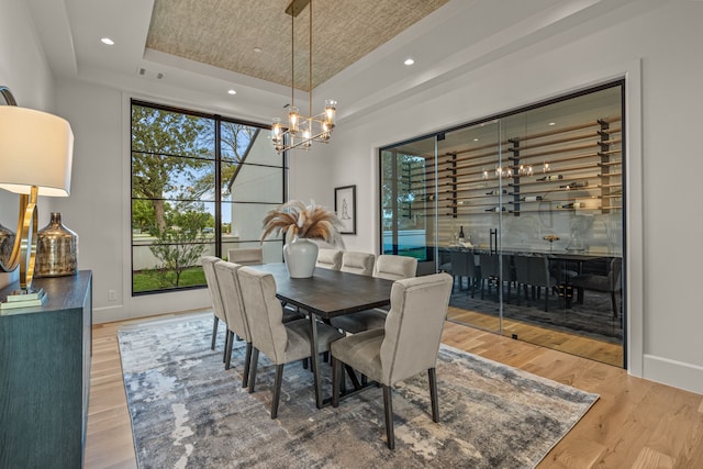 dining area with a tray ceiling, hardwood / wood-style flooring, and a chandelier