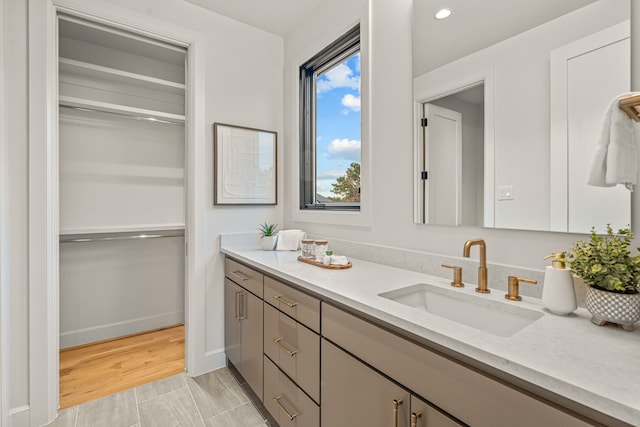 bathroom featuring vanity, recessed lighting, and a walk in closet