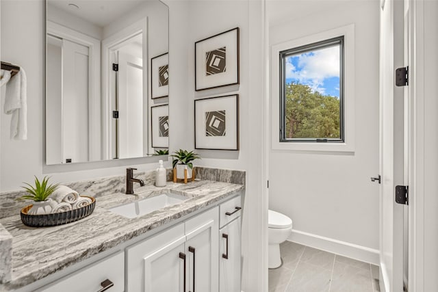 bathroom featuring marble finish floor, baseboards, toilet, and vanity