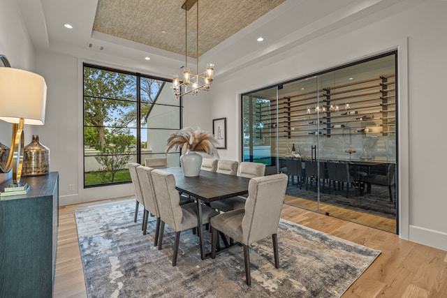 dining room with a chandelier, a raised ceiling, plenty of natural light, and baseboards