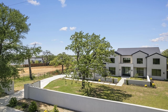 view of front of home featuring fence, a front yard, and metal roof