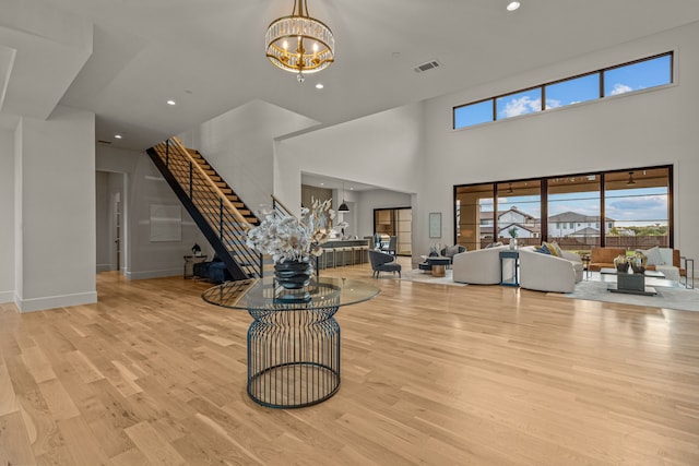 living room with a notable chandelier, light hardwood / wood-style floors, and a high ceiling