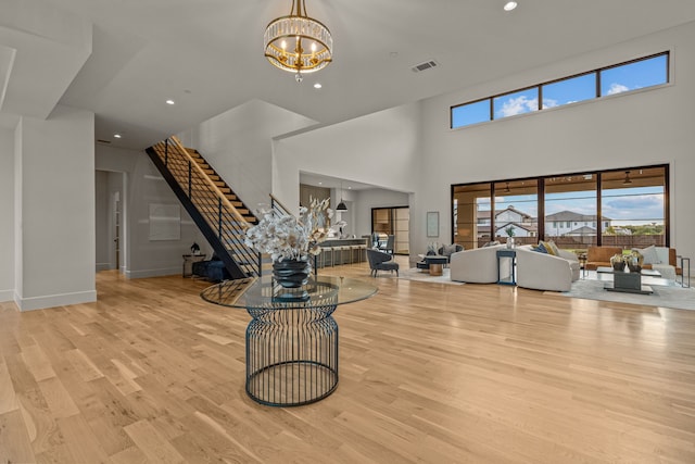 living room with an inviting chandelier, wood finished floors, stairs, and visible vents