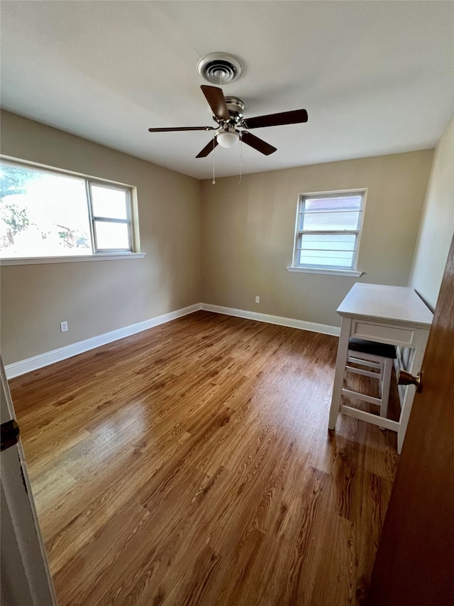 unfurnished room featuring ceiling fan, plenty of natural light, and wood-type flooring