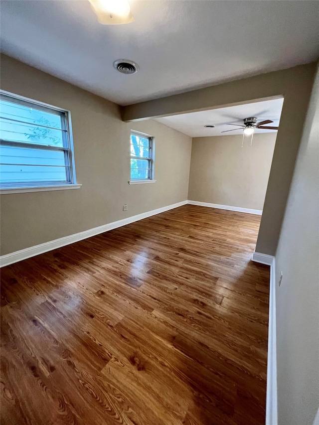 empty room with ceiling fan, hardwood / wood-style flooring, and a wealth of natural light