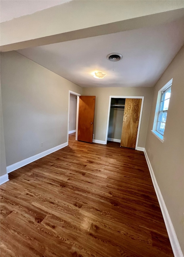 unfurnished bedroom with dark hardwood / wood-style floors and a closet