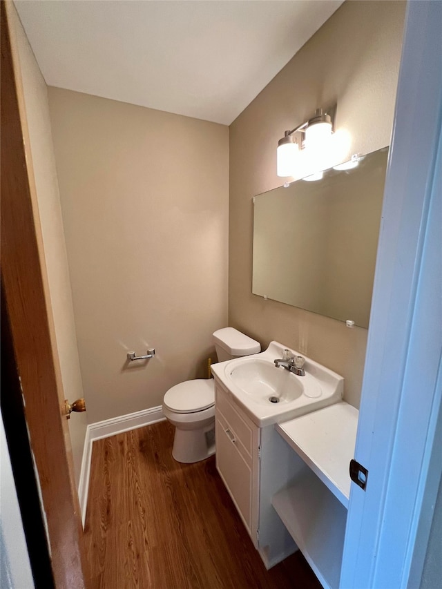 bathroom with wood-type flooring, vanity, and toilet