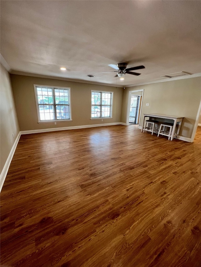 spare room featuring ornamental molding, dark wood-type flooring, ceiling fan, and a wealth of natural light