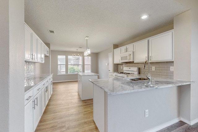 kitchen featuring kitchen peninsula, white cabinetry, and white appliances