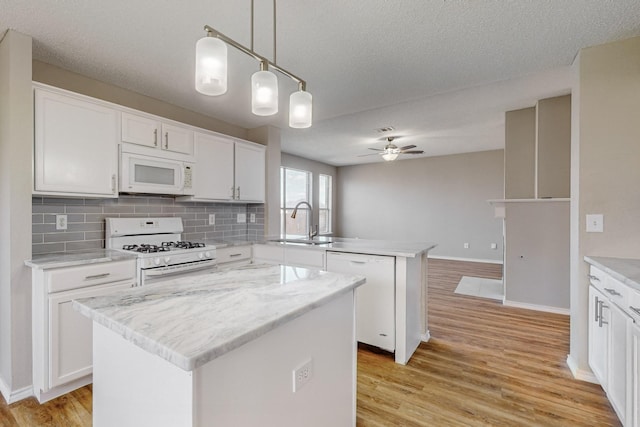 kitchen with a center island, white cabinets, pendant lighting, and white appliances